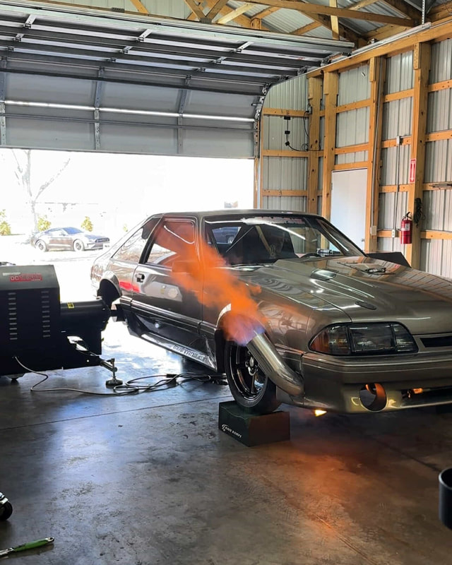 A Fox body Mustang in the open shop bay, flame out the dump