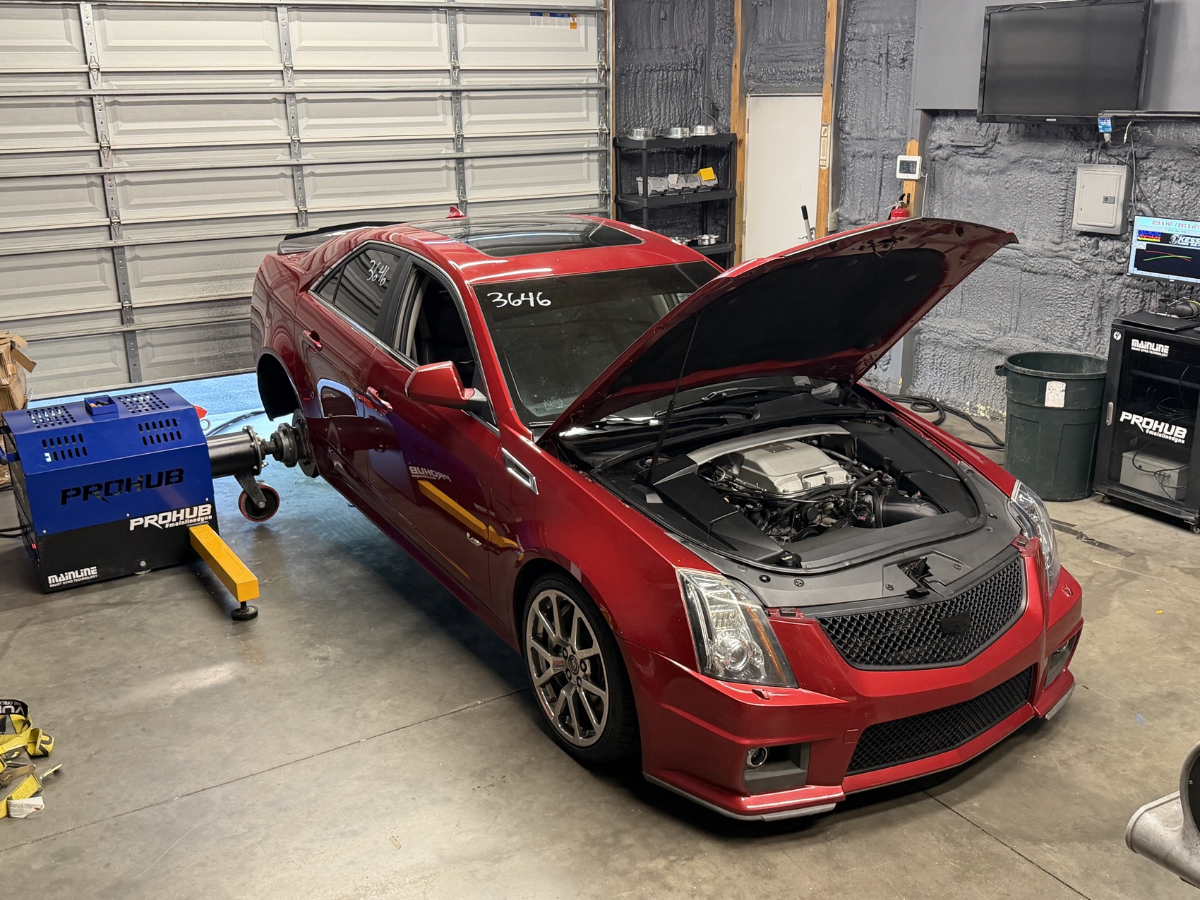 A red Cadillac CTS-V on the dyno hubs in the shop