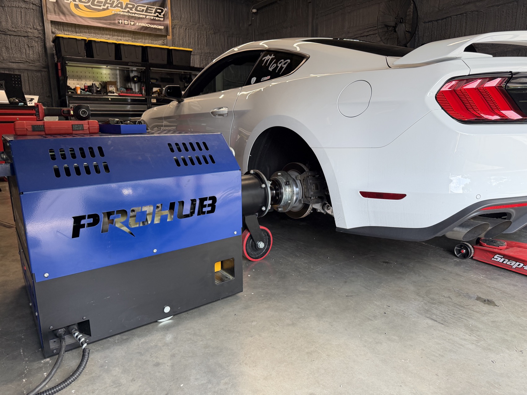 A vehicle bolted to the dyno hubs in the shop bay