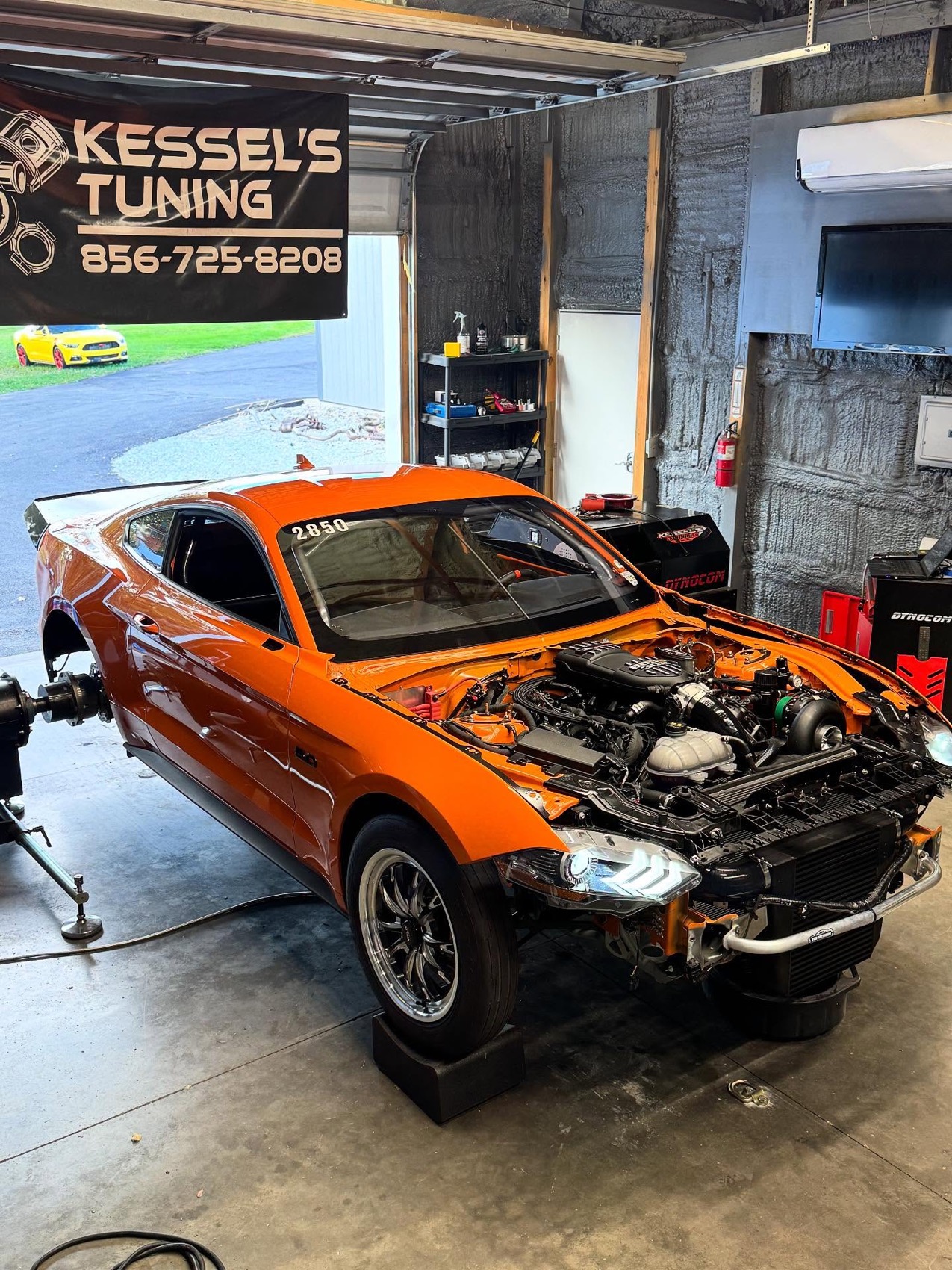 An orange twin turbo Mustang on the dyno at the shop